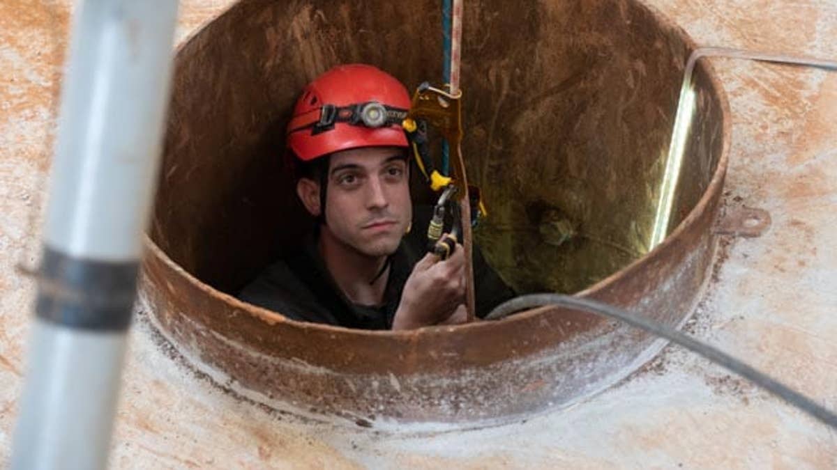 Trey Yingst being lowered into a Hezbollah tunnel using repurposed climbing equipment.