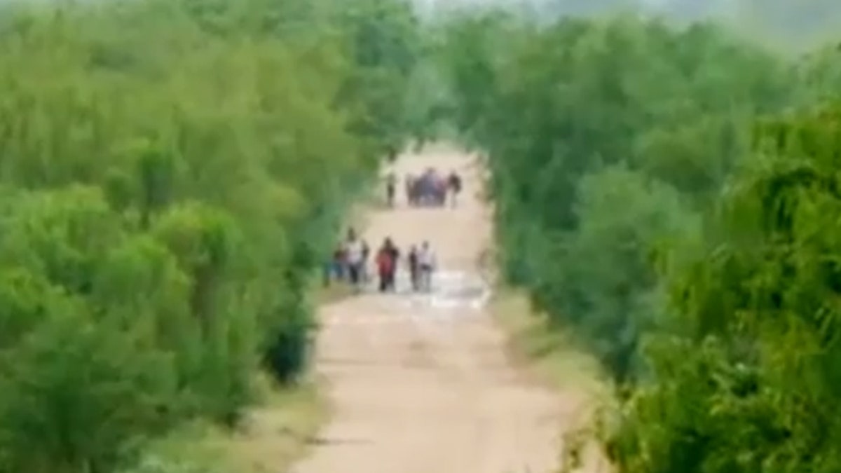 Migrants are seen walking down a road at a portion of the U.S.-Mexico border one top official is calling "ground zero" for illegal crossings.