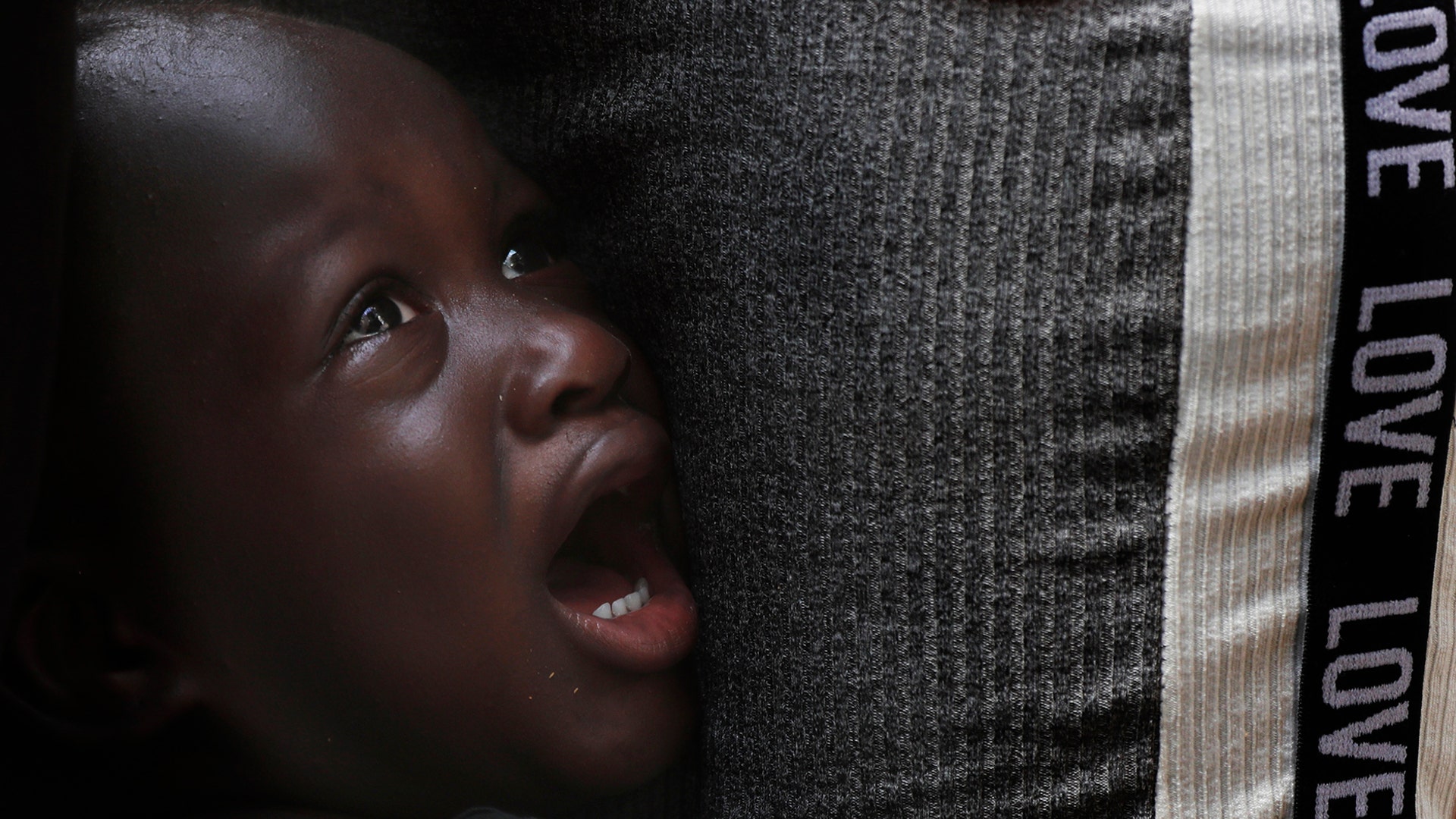 A Haitian migrant youth cries next to his father as they wait in line to solve their migratory situation at an immigration center in Tapachula, Chiapas state, Mexico, May 28, 2019. 
