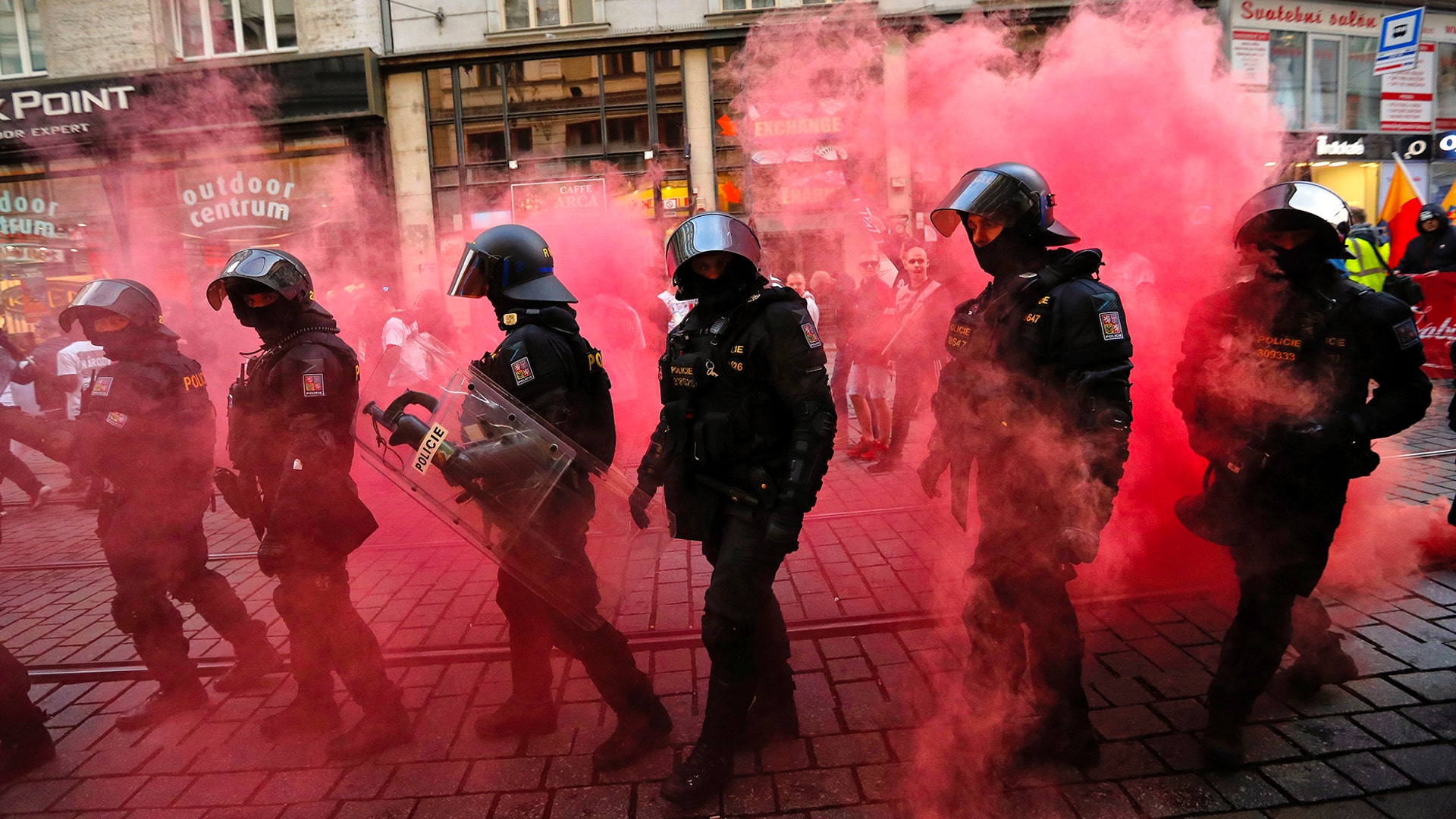 Smoke from flares engulfs riot police officers as they walk along with marching right-wing supporters following scuffles with left-wing protesters in the city of Brno, Czech Republic, May 1, 2019.