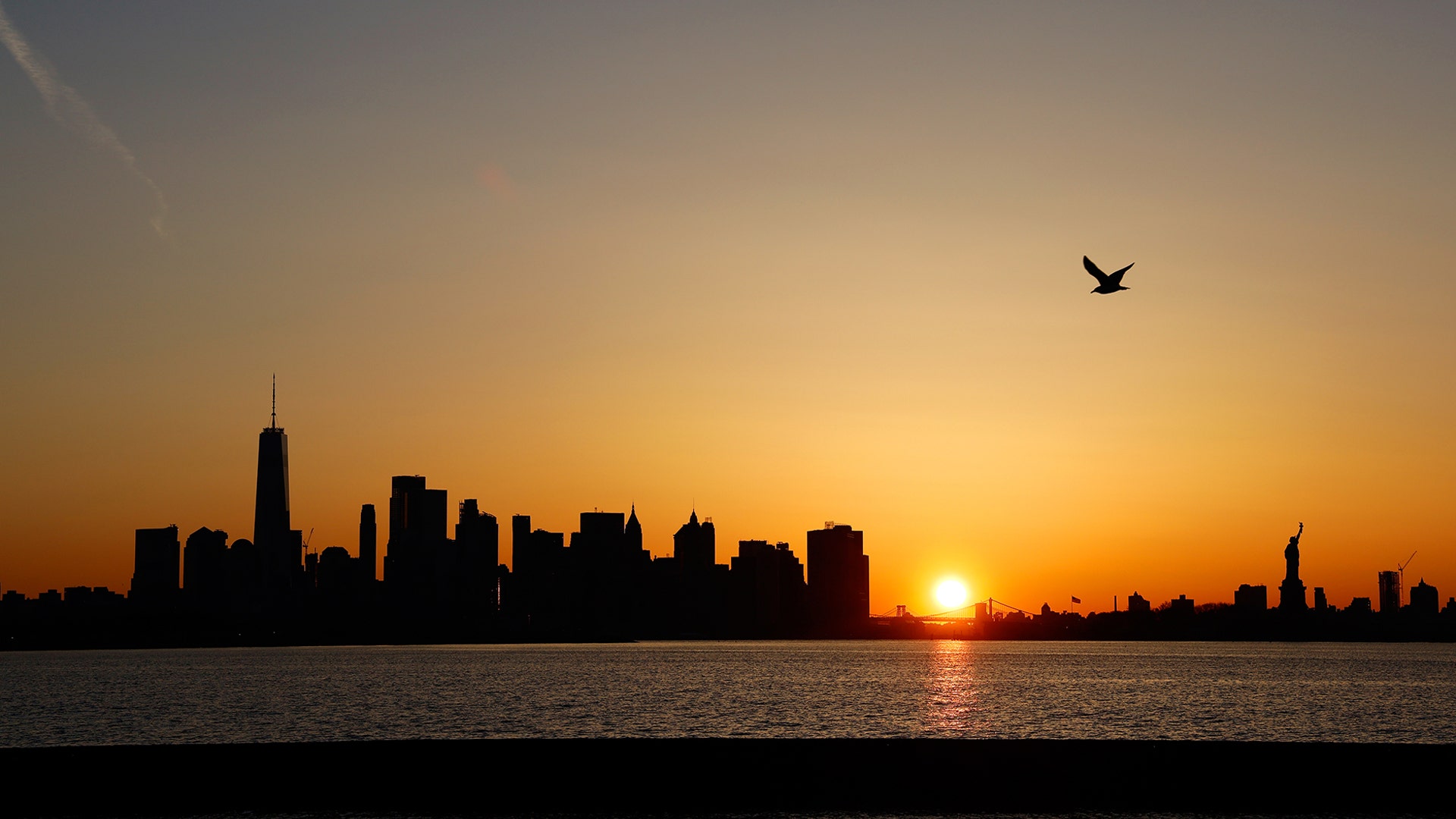 The sun rises behind the skyline of lower Manhattan, One World Trade Center and the Statue of Liberty in New York City, April 29, 2019.