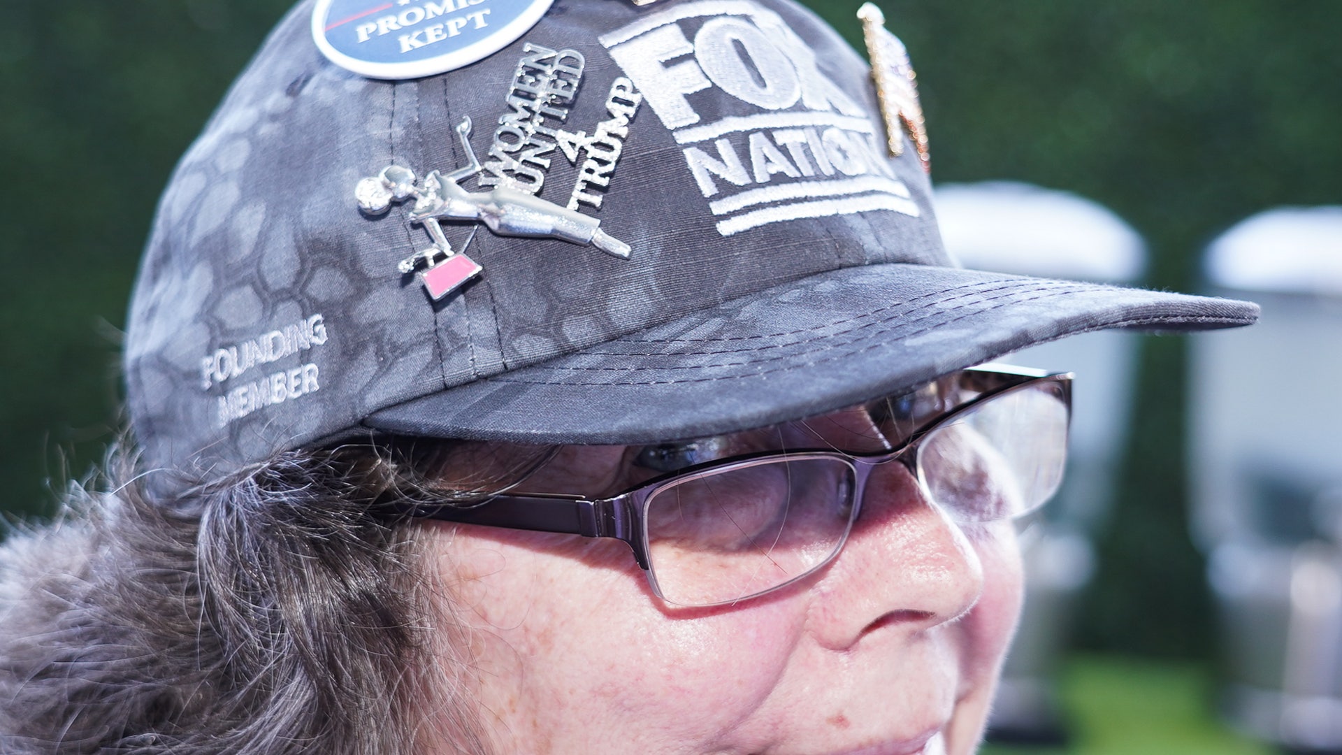 A fan shows off her Fox Nation cap decorated with buttons, including one for "Women United 4  Trump."