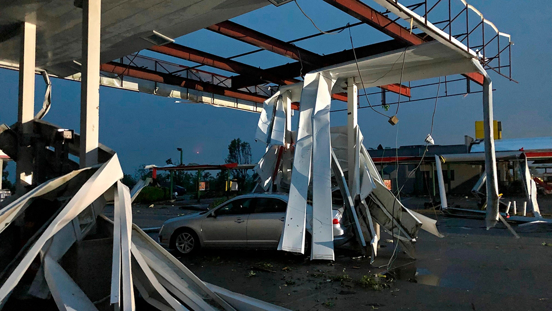 A car is trapped under the fallen metal roof of the Break Time gas station and convenience store. (AP Photo/David A. Lieb)