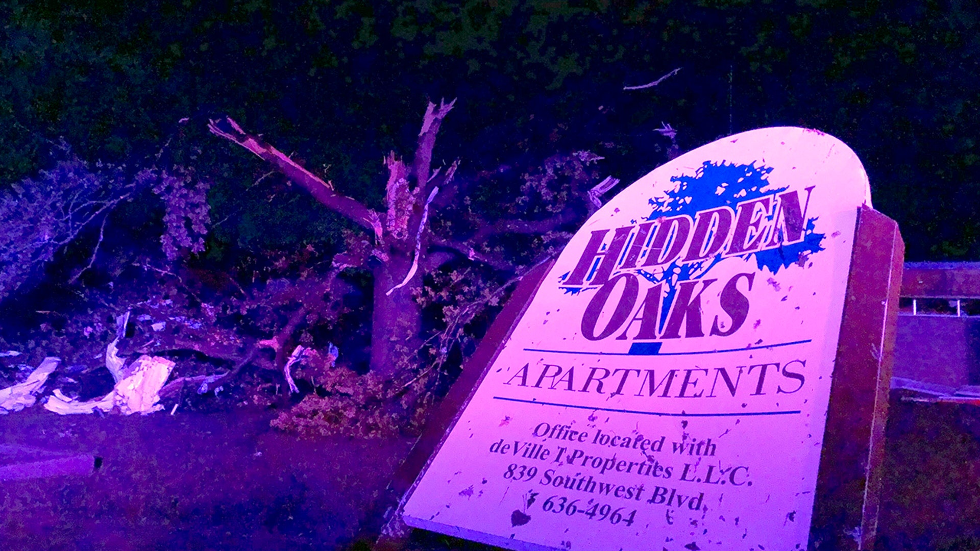 The sign for the Hidden Oaks apartment complex in Jefferson City stands bent from a tornado in front of a tree that was ripped apart. (AP Photo/David A. Lieb)