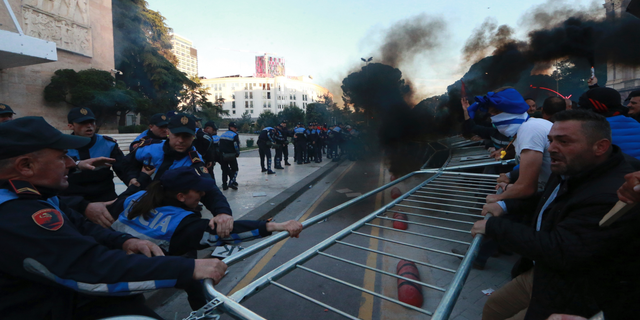 Protesters try to remove a metal fence during clashes with police outside the Government building in Tirana, Saturday, May 11, 2019. Thousands of supporters of the Albania's center-right opposition protested in Tirana Saturday, calling for the left-wing government to resign and for an early parliamentary election. (AP Photo/Hektor Pustina)