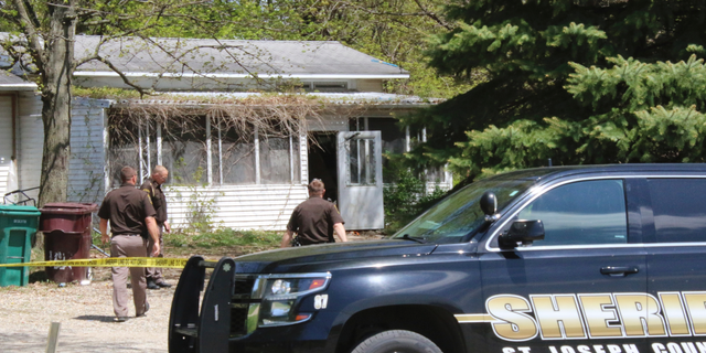 In this Monday, May 6, 2019 photo, St. Joseph County Sheriff deputies stand outside the site where a woman was fatally shot in Fawn River Township, Mich. Authorities say a 9-year-old is suspected in the shooting of a woman in her southern Michigan home. (Corky Emrick/Sturgis Journal via AP)