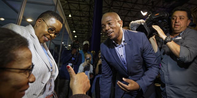 Mmusi Maimane, leader of the largest opposition party, the Democratic Alliance, is greeted by a supporter as he visits the Independent Electoral Commission Results Center in Pretoria, South Africa Thursday, May 9, 2019. South Africans voted Wednesday in a national election and preliminary results show that the ruling African National Congress party (ANC) has an early lead in the national elections but has seen its share of the vote drop significantly.