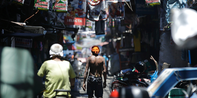 In this Thursday, May 9, 2019, photo, a man walks past election banners in the slum district of Tondo, Manila, Philippines. Philippine President Rodrigo Duterte's name is not on the ballot but Monday's mid-term elections are seen as a referendum on his phenomenal rise to power, marked by his gory anti-drug crackdown and his embrace of China. (AP Photo/Aaron Favila)