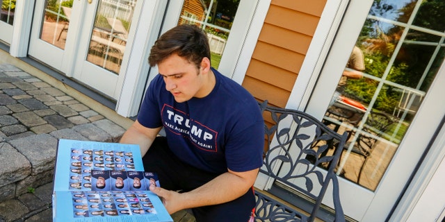 In this June 2017 photo, Wall High School student Grant Berardo is seen flipping through his 2017 school yearbook. The yearbook included a photo of him wearing a digitally altered T-shirt that originally included the words "Trump Make America Great Again."