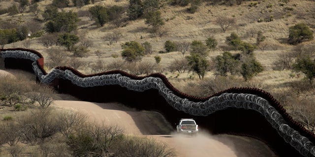 FILE - This March 2, 2019, file photo, shows a Customs and Border Control agent patrolling on the US side of a razor-wire-covered border wall along the Mexico east of Nogales, Ariz. (AP Photo/Charlie Riedel, File)