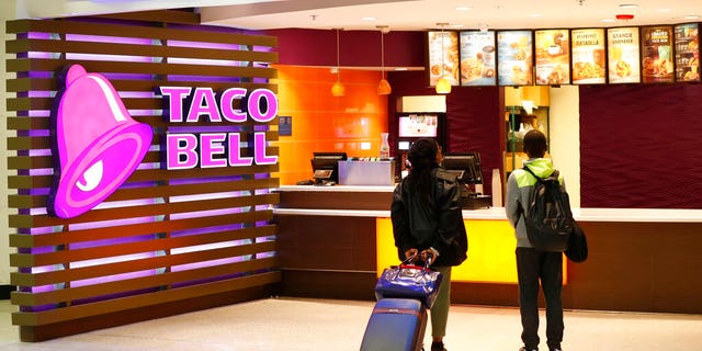 FILE: Travelers look at a menu at a Taco Bell restaurant inside Miami International Airport in Miami. (Associated Press)
