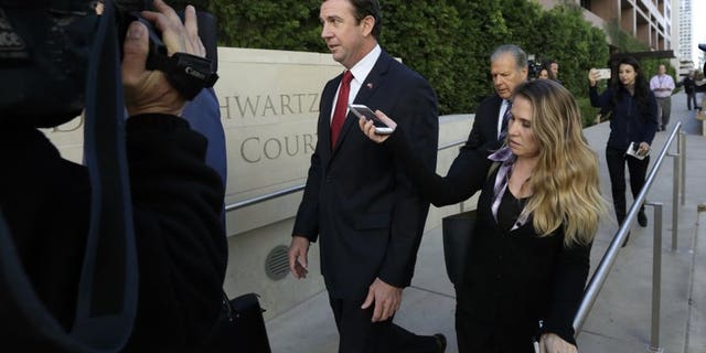 FILE - In this Dec. 3, 2018 file photo Republican Rep. Duncan Hunter, center, leaves court in San Diego..