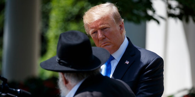 President Donald Trump looks on as Rabbi Yisroel Goldstein, survivor of the Poway, Calif synagogue shooting, speaks during a National Day of Prayer event in the Rose Garden of the White House, Thursday, May 2, 2019, in Washington. (AP Photo/Evan Vucci)