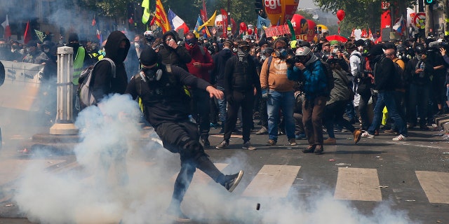 An activist kicks off a tear gas tank during a May Day demonstration in Paris. (AP Photo / Francois Mori)