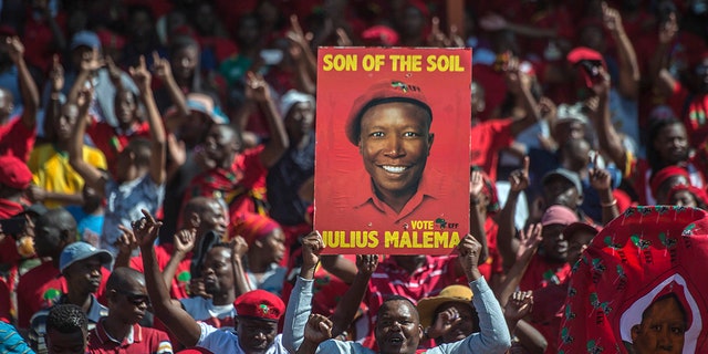 Supporters of the Economic Freedom Fighters (EFF) party, hold up an election poster of leader Julius Malema during a May Day Rally in Alexandra Township, Johannesburg, Wednesday, May 1, 2019. (AP Photo/Mujahid Safodien)