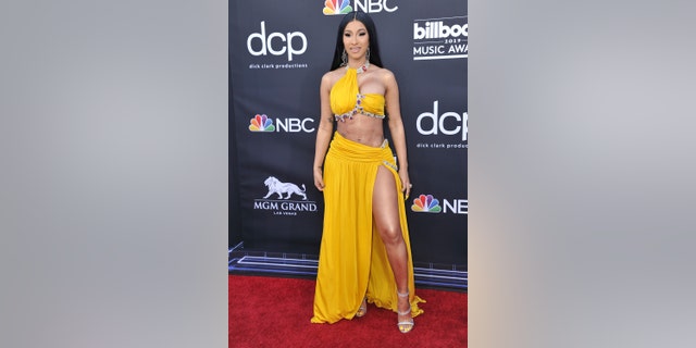 Cardi B rocks a yellow two piece outfit with jewel detailing.
