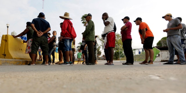 In this April 30, 2019, photo, migrants seeking asylum in the United States line up for a meal provided by volunteers near the international bridge in Matamoros, Mexico. (AP Photo/Eric Gay)