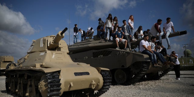 Students sit on a tank just before a ceremony marking the annual Memorial Day to remember fallen soldiers and victims of terror, at the Armored Corps memorial site in Latrun, Israel, Wednesday, May 8, 2019. (AP Photo/Oded Balilty)