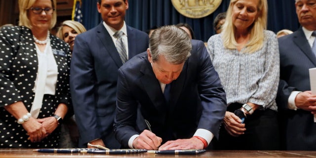 FILE - In this May 7, 2019, file photo, Georgia's Republican Gov. Brian Kemp, center, signs legislation in Atlanta, banning abortions once a fetal heartbeat can be detected, which can be as early as six weeks before many women know they're pregnant. Georgia became the fourth state to enact the ban on abortions after a fetal heartbeat can be detected. (Bob Andres/Atlanta Journal-Constitution via AP, File)