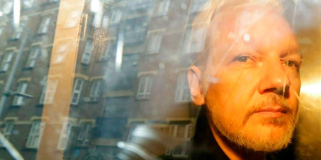 In this Wednesday, May 1, 2019, file photo, buildings are reflected in the window as WikiLeaks founder Julian Assange is taken from court, where he appeared on charges of jumping British bail seven years ago, in London. (AP Photo/Matt Dunham)