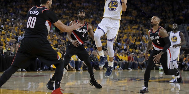 Golden State Warriors' Stephen Curry (30) shoots between Portland Trail Blazers' Maurice Harkless (4), Enes Kanter (00) and Damian Lillard, right, during the first half of Game 1 of the NBA basketball playoffs Western Conference finals Tuesday, May 14, 2019, in Oakland, Calif.