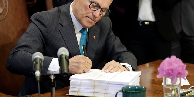 Washington Gov. Jay Inslee signs the state operating budget, Tuesday, May 21, 2019, at the Capitol in Olympia, Wash. Inslee also signed a sanctuary state measure on Wednesday. (AP Photo/Ted S. Warren)