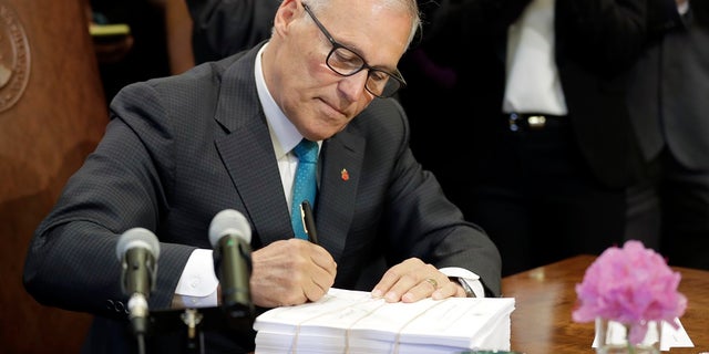Washington Gov. Jay Inslee signs the state operating budget, Tuesday, May 21, 2019, at the Capitol in Olympia, Wash. Inslee also signed a “sanctuary state” measure on Wednesday. (AP Photo/Ted S. Warren)