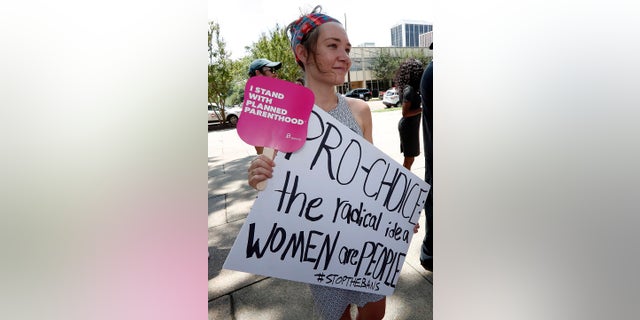 Abbey Williams of Brandon, Miss.  holds a sign at the Capitol in Jackson, Miss., voicing her opposition to state legislatures passing abortion bans that prohibit most abortions once a fetal heartbeat can be detected, Tuesday, May 21, 2019. In addition, there are no provisions for rape or incest. Mississippi is among the states that have passed and signed into law such legislation. (AP Photo/Rogelio V. Solis)