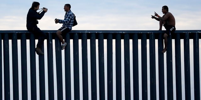 In this archival photo of November 21, 2018, two Hondurans posing as photographers, on the left, take their picture after the group climbed the border wall separating Tijuana (Mexico) and San Diego, before descending to the Mexican side. , seen from San Diego. (AP Photo / Gregory Bull, File)