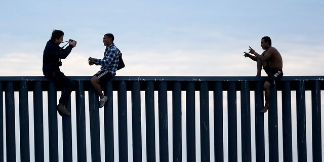 In this archival photo of November 21, 2018, two Hondurans posing as photographers, on the left, take their picture after the group climbed the border wall separating Tijuana (Mexico) and San Diego, before descending to the Mexican side. , seen from San Diego. (AP Photo / Gregory Bull, File)