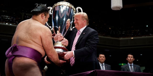 President Trump presents the "President's Cup" to the Tokyo Grand Sumo Tournament winner Asanoyama, at Ryogoku Kokugikan Stadium, on Sunday, in Tokyo. (Associated Press)