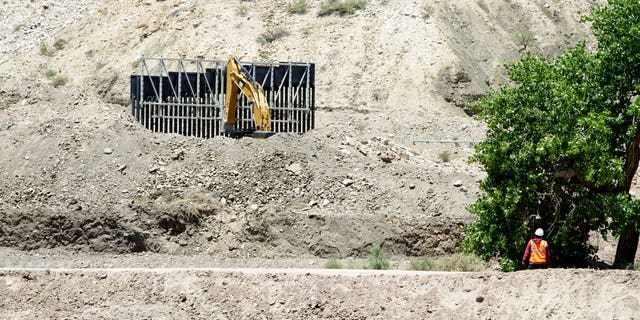 FILE: A construction worker watches a section of fencing be moved for a privately-funded border fence on private land in Sunland Park, New Mexico.