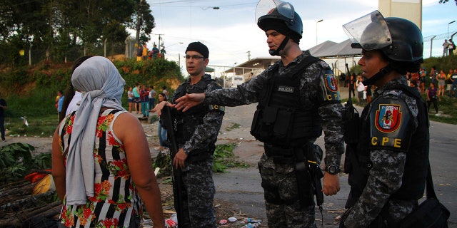 A woman asks police officers for more information outside the Anisio Jobim Prison Complex in Manaus, Amazonas state, Brazil, Monday, May 27, 2019. (AP Photo/Edmar Barros)