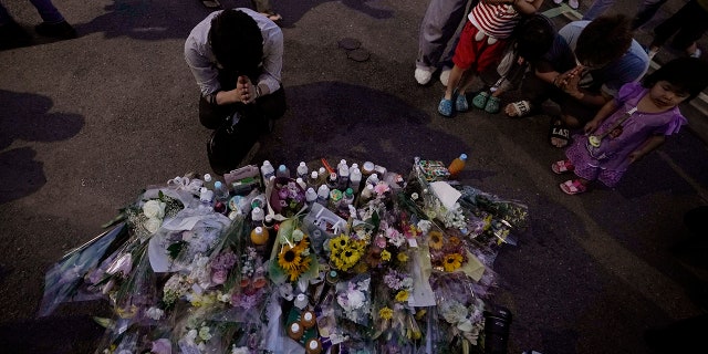 People pay their respects at a makeshift memorial for the victims of a knife attack Tuesday, May 28, 2019, in Kawasaki, just outside Tokyo. (AP Photo/Jae C. Hong)