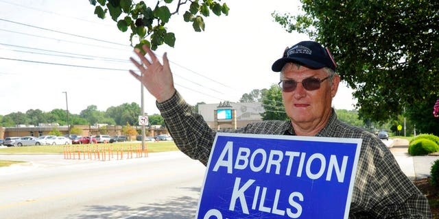 Jim Snavelly aus Huntsville, Alabama, winkt vorbeifahrenden Autos zu, während er ein Anti-Abtreibungs-Schild vor dem Alabama Women's Health Center in Huntsville hält, 17. Mai 2019. (AP Photo/Eric Schultz)