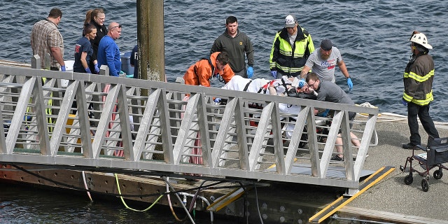 An injured passenger is helped to an ambulance after two floatplanes collided near Ketchikan, Alaska Monday afternoon. (Dustin Safranek/Ketchikan Daily News via AP)