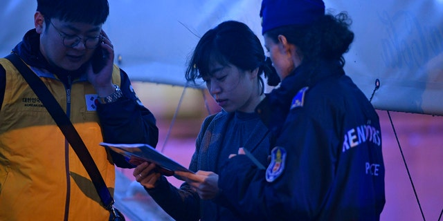 South Korean Embassy personnel help identifying the victims of an accident during a search operation for survivors on the River Danube in downtown Budapest, Hungary, Thursday, May 30, 2019. (Zsolt Szigetvary/MTI via AP)