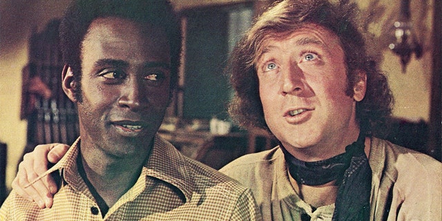 Actor Gene Wilder (right) puts his arm around the shoulder of Cleavon Little in a still from the film, 'Blazing Saddles,' directed by Mel Brooks, 1974. (Photo by Warner Bros./Courtesy of Getty Images)