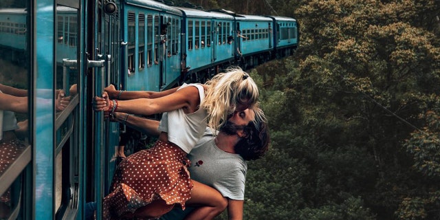 Influencers Jean and Camille, of the BackpackDiariez Instagram handle, were photographed gripping onto the side of a blue train while leaning out for a risky kiss in Sri Lanka.