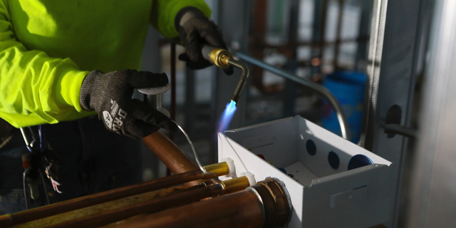 FILE- In this Jan. 24, 2019, file photo, Zakiyyah Askia, a plumbing apprentice in a program run by the nonprofit Chicago Women in Trades, welds pipes at a high rise residence under construction in Chicago. On Friday, May 3, the Institute for Supply Management, a trade group of purchasing managers, issues its index of non-manufacturing activity for April. (AP Photo/Teresa Crawford, File)