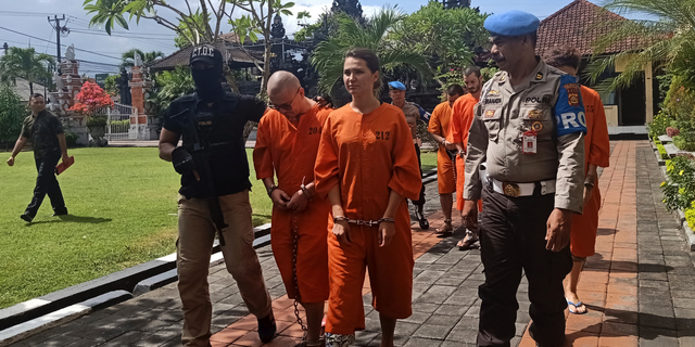 Police officers escort foreign nationals arrested for selling drugs prior to a press conference at the regional police headquarters in Denpasar, Bali, Indonesia, Friday, May 31, 2019. Police on the resort island have arrested an American, two Spaniards and two Russians for selling cocaine on the island.