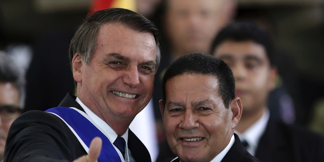 Brazil's President Jair Bolsonaro flashes a thumbs up after bestowing the insignia of the Order of Rio Branco to Vice President Hamilton Mourao, right, during a ceremony to commemorate Diplomat Day, at the Itamarty Palace in Brasilia, Brazil, Tuesday, May 3, 2019. (AP Photo/Eraldo Peres)