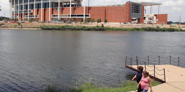 FILE - In this July 2, 2014, file photo, people stroll along the river across from the new McClane Stadium at Baylor University in Waco, Texas. Baylor University has announced a $100 million donation that administrators say is the largest gift in school history. The announcement Saturday night, May 4, 2019, in Waco, said the donor wishes to remain anonymous with the donation earmarked for Baylor's $1.1 billion Give Light philanthropic campaign that includes teaching, research and service. Baylor is the world's largest Baptist university, with enrollment of about 17,000. (Jerry Larson/Waco Tribune-Herald via AP, File)