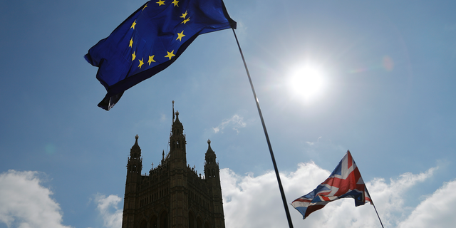 FILE - In this Thursday, April 11, 2019 file photo, protestor flags fly opposite the Houses of Parliament in London. The British economy is likely to weaken as firms stop ease up on Brexit preparations now that Britain’s departure from the European Union has been delayed by months, the Bank of England said Thursday, May 2, 2019. (AP Photo/Frank Augstein, File)