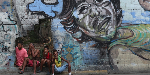 A group of young people rest in a hole in the wall at the Agua Salud neighborhood of Caracas, Venezuela, Wednesday, May 15, 2019. More than 3 million Venezuelans have left their homeland in recent years amid skyrocketing inflation and shortages of food and medicine. U.S. administration officials have warned that 2 million more are expected to flee by the end of the year if the crisis continues in the oil-rich nation. (AP Photo/Martin Mejia)