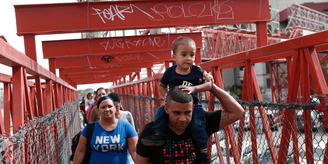 In this April 29, 2019, photo, Cuban migrants are escorted in Ciudad Juarez, Mexico, by Mexican immigration officials as they cross the Paso del Norte International bridge to be processed as asylum seekers on the U.S. side of the border. U.S. authorities have been telling asylum seekers that they are at capacity and to return when space opens up, a hands-off approach that has created haphazard and often-dubious arrangements in Mexico.  (AP Photo/Christian Torres)