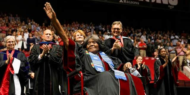 This photo provided by UA Strategic Communications Autherine Lucy Foster acknowledges the crowd as she receives a an honorary doctoral degree during a commencement exercise at The University of Alabama on Friday, May 3, 2019 in Tuscaloosa, Ala.  The university bestowed the honorary doctorate degree to Foster, the first African American to attend the university.  (Zach Riggins/UA Strategic Communications via AP)