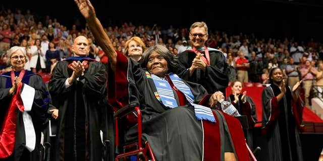 This photo provided by UA Strategic Communications Autherine Lucy Foster acknowledges the crowd as she receives a an honorary doctoral degree during a commencement exercise at The University of Alabama on Friday, May 3, 2019 in Tuscaloosa, Ala. The university bestowed the honorary doctorate degree to Foster, the first African American to attend the university. (Zach Riggins/UA Strategic Communications via AP)