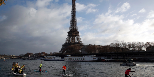 FILE - In this Dec.9, 2018 file photo, competitors paddle on the Seine river in front of the Eiffel Tower in Paris. The Eiffel Tower press office said Monday May 20, 2019 an unidentified individual tried to scale the near-300 meter (near-328 yard) monument on Monday afternoon but it wasn't clear how high the climber managed to get. (AP Photo/Christophe Ena, File)