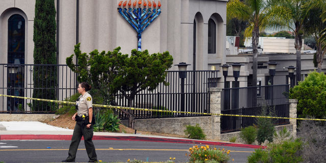 FILE - In this Sunday, April 28, 2019 file photo, a San Diego county sheriff's deputy stands in front of the Poway Chabad Synagogue in Poway, Calif. The gunman who attacked the synagogue last week fired his semi-automatic rifle at Passover worshippers after walking through the front entrance that synagogue leaders identified last year as needing improved security. The synagogue applied for a federal grant to better protect that area. The money, $150,000, was approved in September but only arrived in late March. "Obviously we did not have a chance to start using the funds yet," Rabbi Scimcha Backman told The Associated Press. (AP Photo/Denis Poroy, File)
